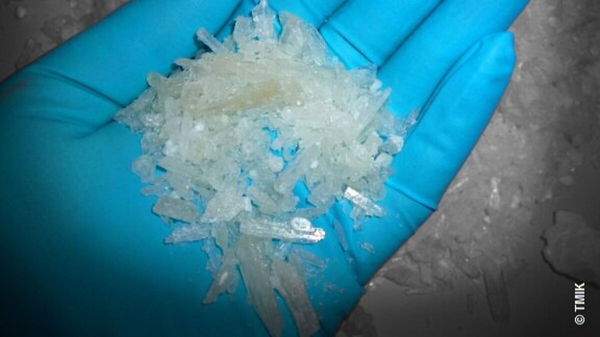 Ein Hand im blauen Handschuh mit Crystal Meth
