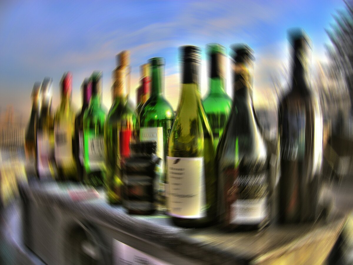 Viele Alkoholflaschen stehen nebeneinander. Das Bild ist verschwommen.