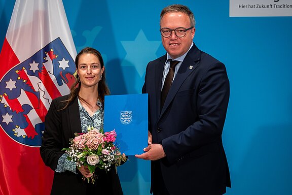 Staatssekretärin Tina Rudolph neben Ministerpräsident Mario Voigt. In den Händen hält sie die Ernennungsurkunde.