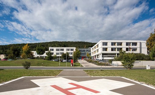 Das Bild zeigt im Vordergrund den Hubschrauberlandeplatz und im Hintergrund das Hauptgebäude des Standorts Rudolstadt der Thüringen-Kliniken „Georgius Agricola“.